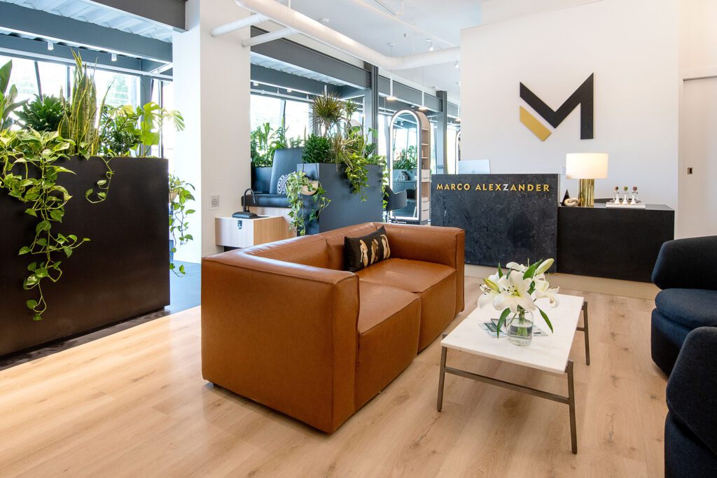 interior of Marco Alexzander salon lobby area with black millwork, plants, and leather couch